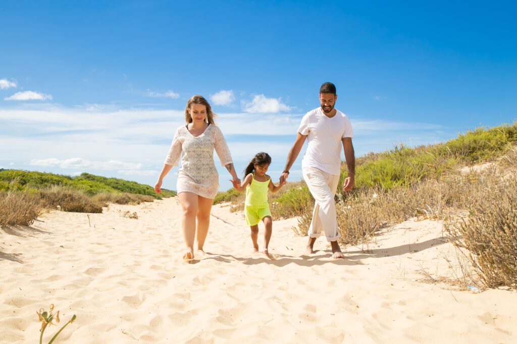 happy family couple little kid summer clothes walking white along sand path girl holding parents hands (1)